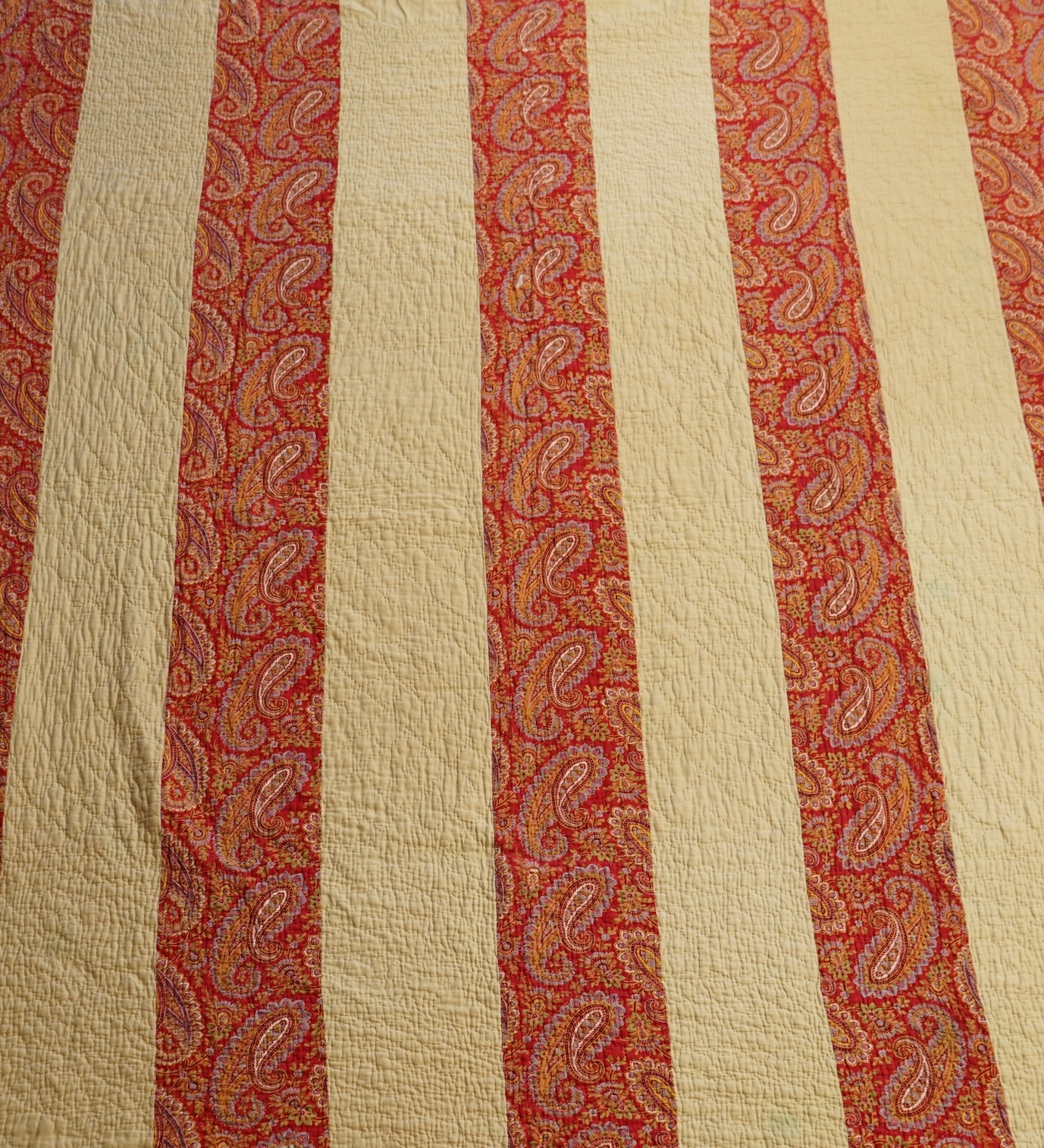An English cotton hexagon hand made and hand pieced quilt, made from a large variety of printed dress fabrics from 19th century. The quilt edged with a wide stripped multi fabric border. The under side designed in wide s